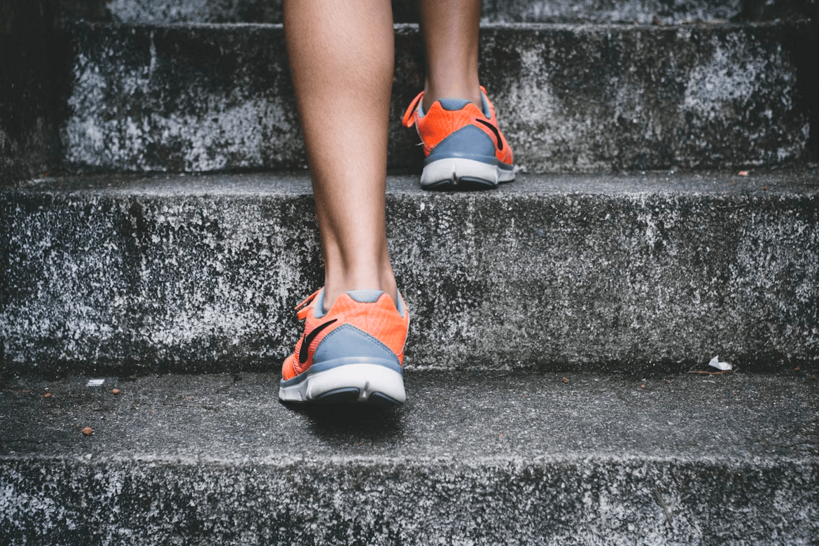 Close up shot of person running up stone steps. Theyre wearing a tracker that allows for step counting.